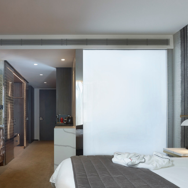 Smart glass panel in a hotel bedroom, featuring low-iron clarity, instant opacity, and sophisticated modern privacy solutions for commercial hospitality.