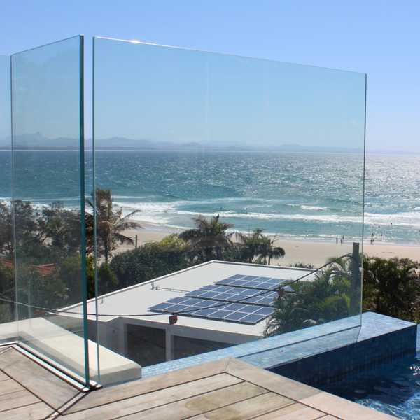 Wide-angle view of a residential pool area featuring frameless toughened glass panels, maximizing natural light and showcasing the stunning Byron Bay coastal backdrop.