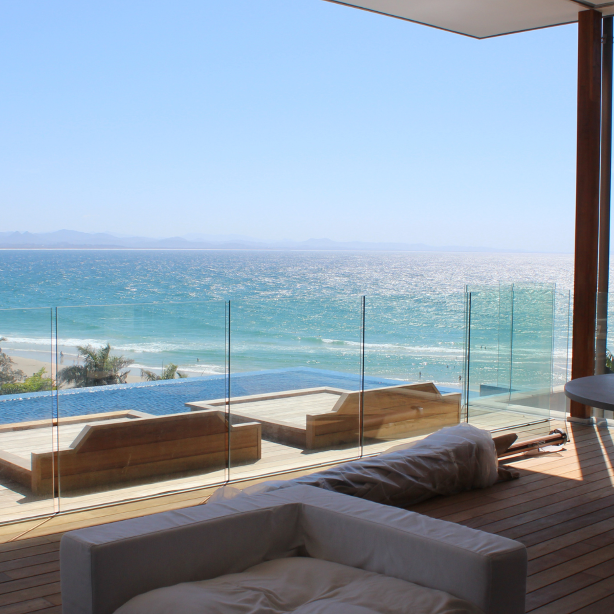 rameless 13.52 mm clear toughened Polystrong structural balustrade glass surrounding a residential swimming pool in Byron Bay, offering uninterrupted ocean views and modern coastal elegance.