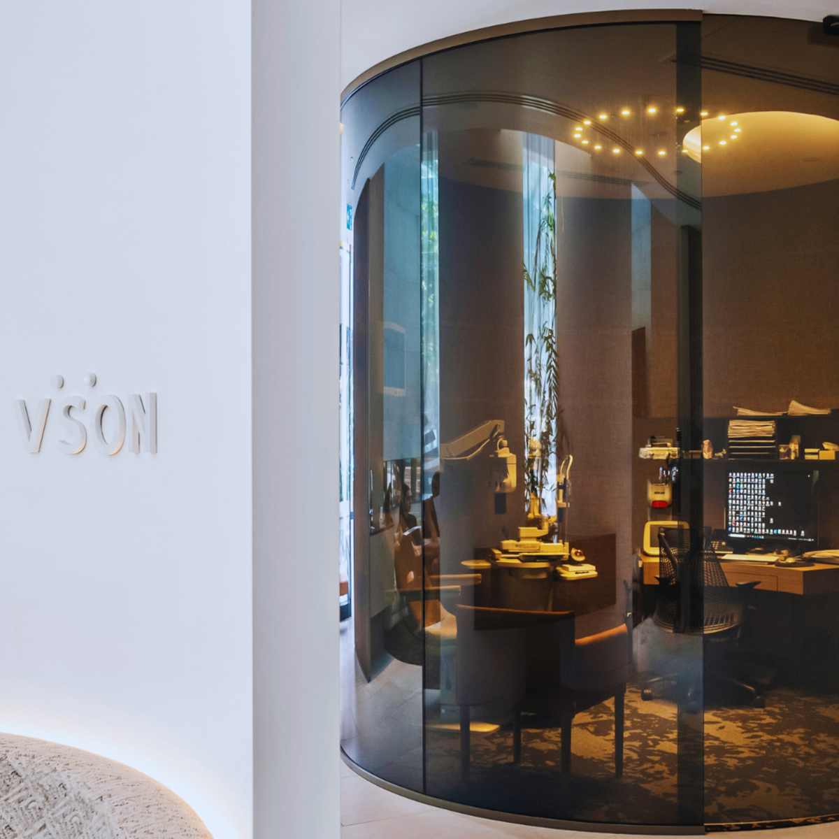 Grey switchable smart glass installation in a laser eye surgery consultation room, featuring curved toughened laminated glass panels for instant privacy and modern clinical design.