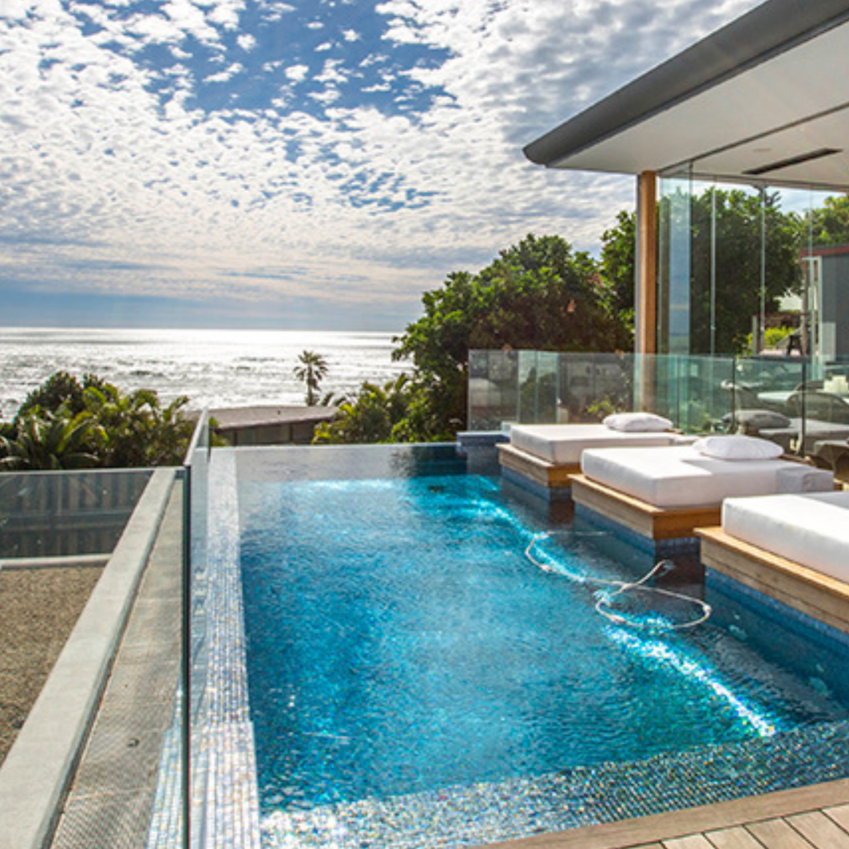 Detail of Polystrong structural balustrade glass around a pool, highlighting seamless design, coastal durability, and modern minimalist aesthetics for outdoor luxury spaces.